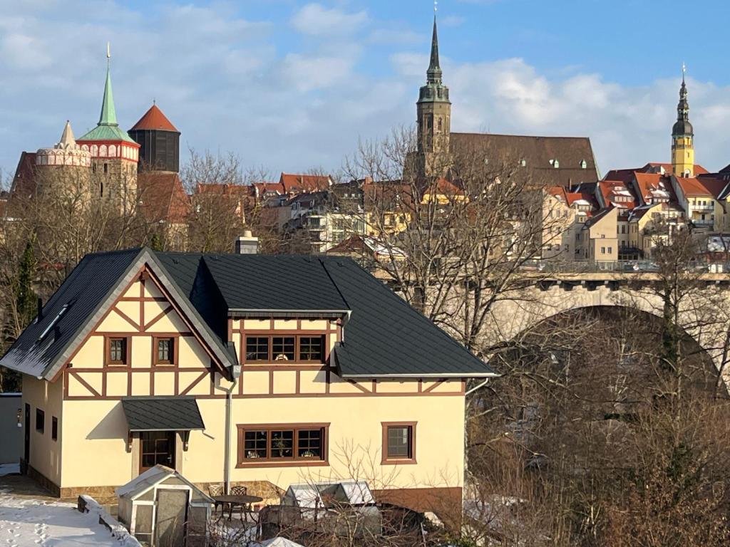 a house with a black roof in front of a city at Ferienhaus Sprejnik Bautzen in Bautzen