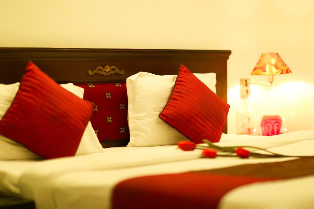 Habitación de hotel con 2 camas con almohadas rojas en Hotel Kamla Palace, en Dehradun