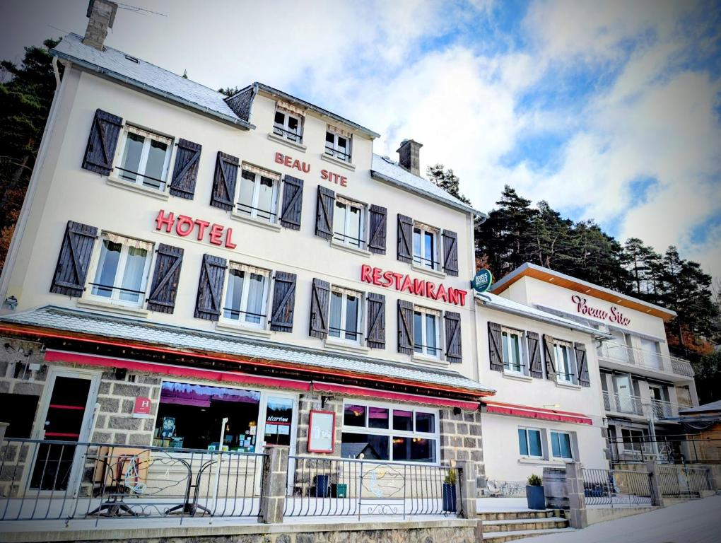 a large white building with windows on a street at Logis Hôtel Restaurant SPA le Beau Site in Chambon-sur-Lac