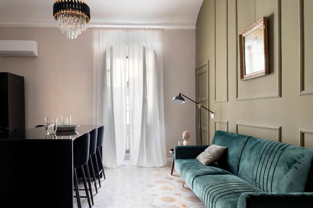 a living room with a green couch and a table at Ziolì Apartment in Noto