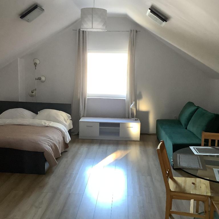 a bedroom with a bed and a couch and a window at Nad stawami in Wilka