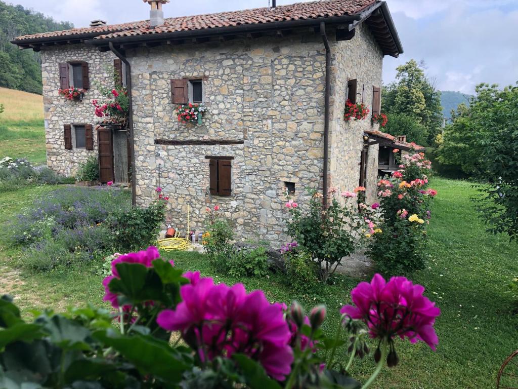 a stone house with flowers in front of it at La Piana Dei Castagni in Castel dʼAiano