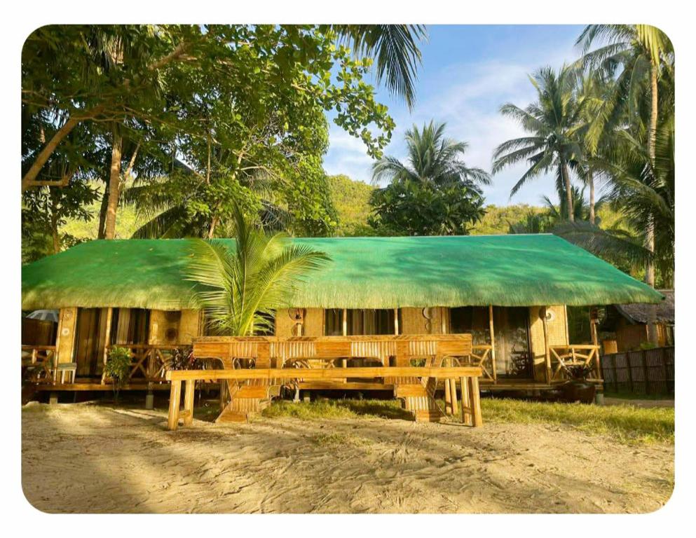a building with a green roof and wooden benches at Ocam Ocam Bayside Lodge in Busuanga