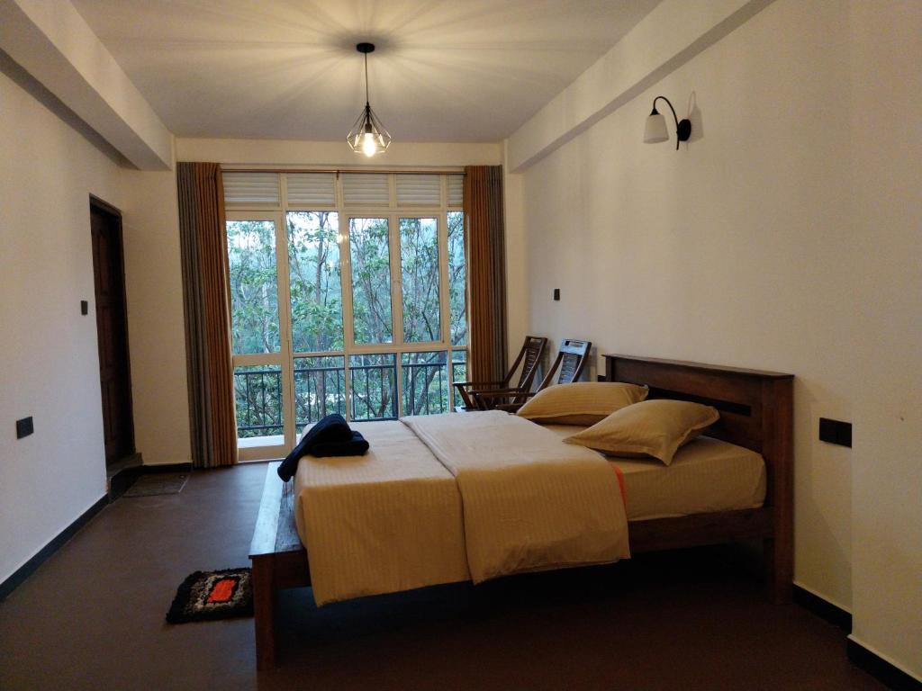 a bedroom with a bed and a large window at Isha Unity Cottage in Nallathanniya