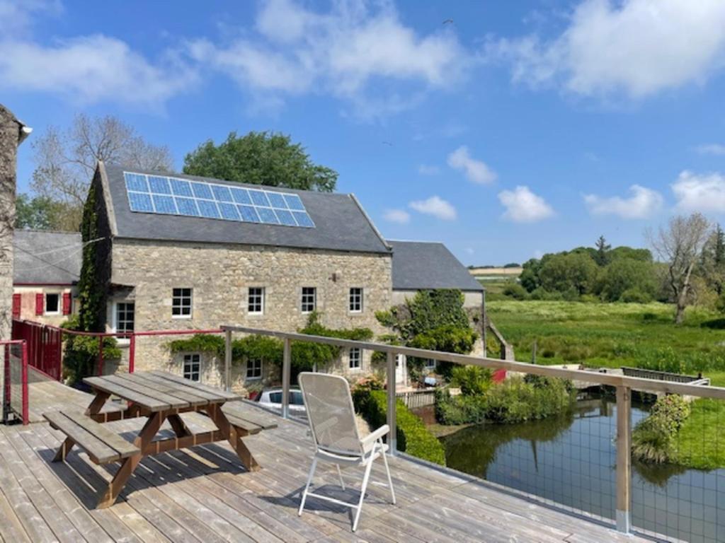 a wooden deck with a picnic table and a house with a solar roof at Gîte Sieck Moulin de Kerellec in Plougoulm