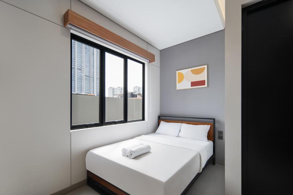 a small bedroom with a bed and a window at Cove Alexa in Jakarta