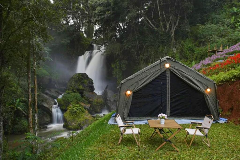 a tent with a table and chairs in front of a waterfall at Doi Inthanon Waterfall Garden in Ban Sop Mae Klang