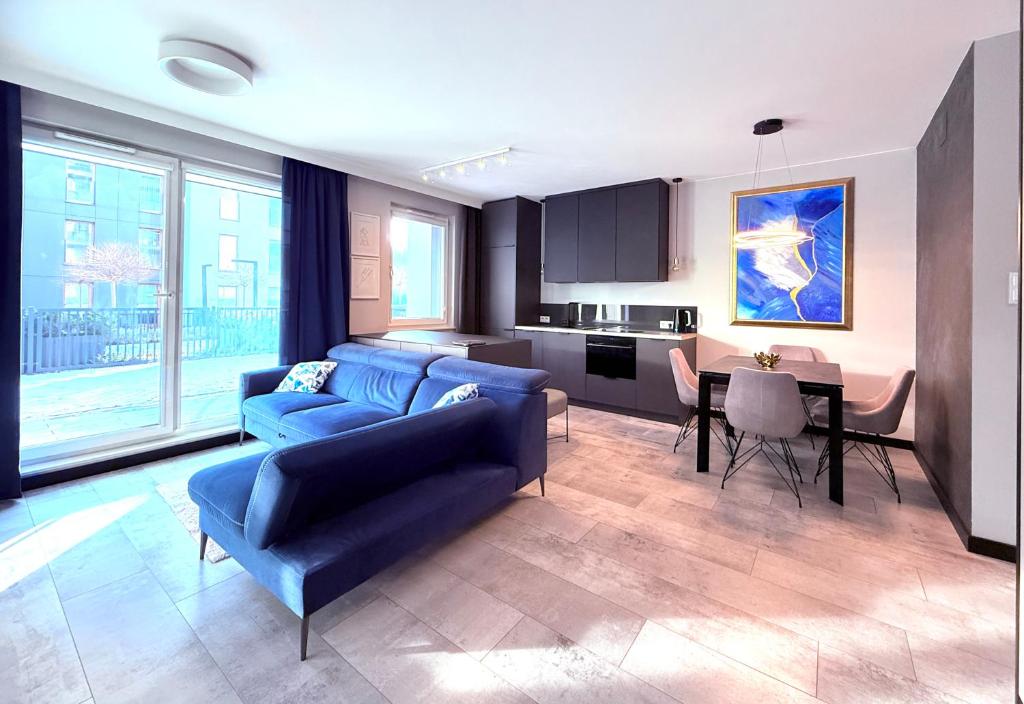 a living room with a blue couch and a kitchen at FARFA Harmonia Oliwska in Gdańsk