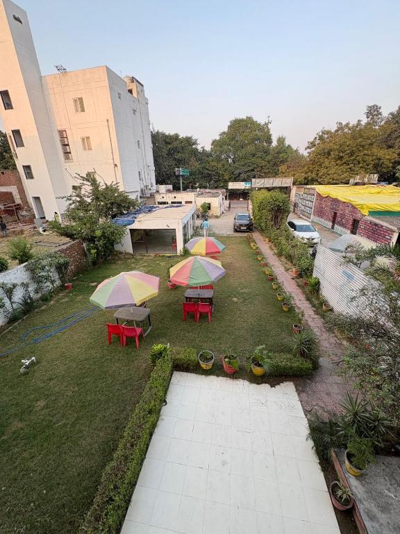 a garden with tables and umbrellas on the grass at AD ressidency Hotel in Agra