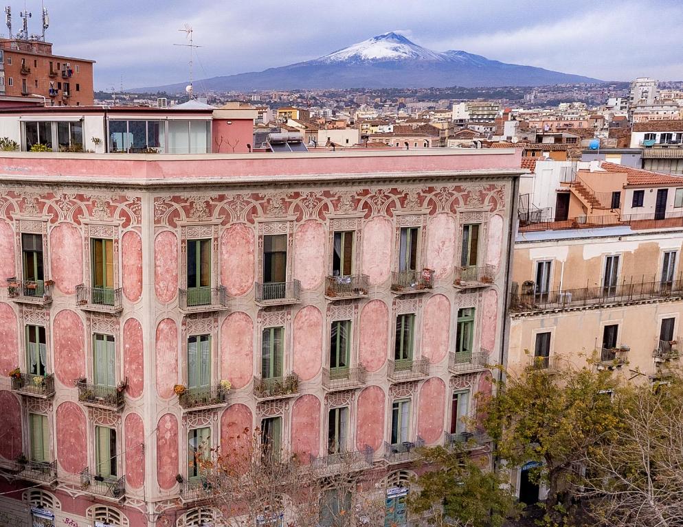 an old building with a snow covered mountain in the background at Promenade B&B in Catania
