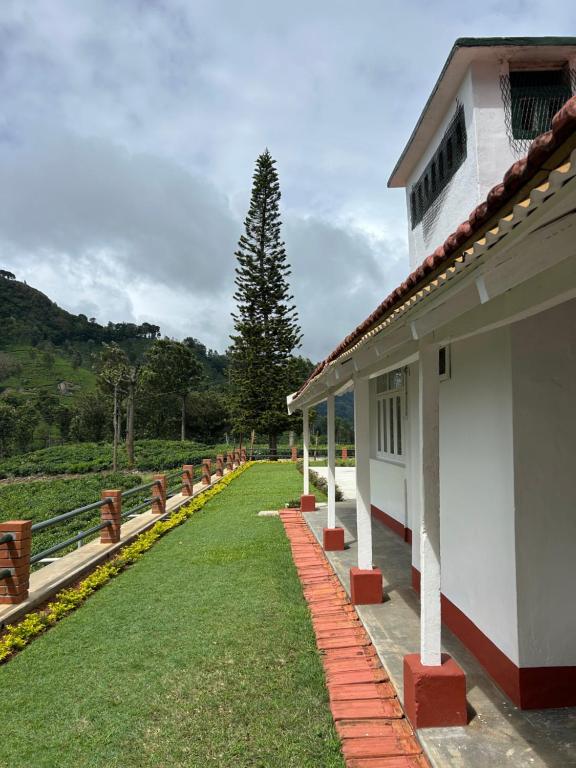 a building with a pathway next to a grass yard at Ellem House in Kotagiri
