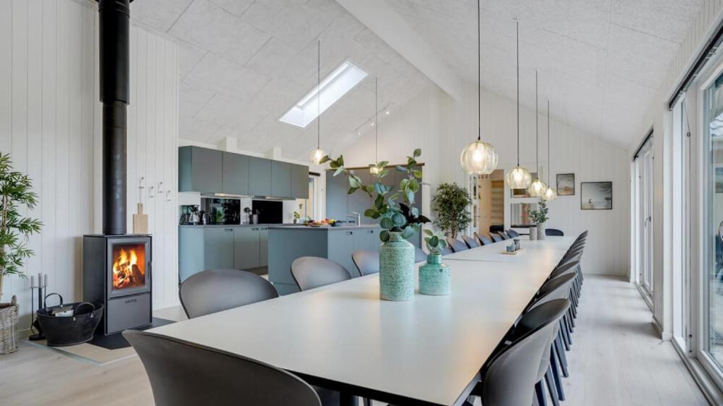 a dining room with a long table and chairs and a fireplace at Villavilla 530 - Mommark, Sydjylland in Sarup