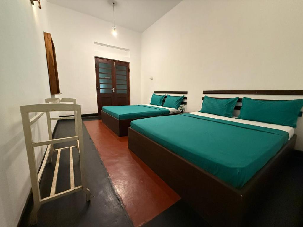 a room with two beds with green sheets and a ladder at Mango Three Resort in Anuradhapura