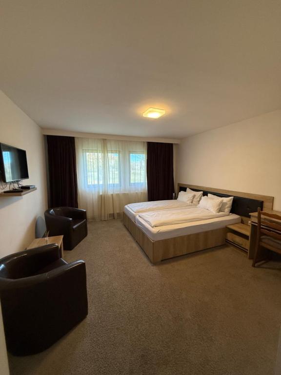 a large bedroom with a bed and a chair at K&I Panzió in Comolău