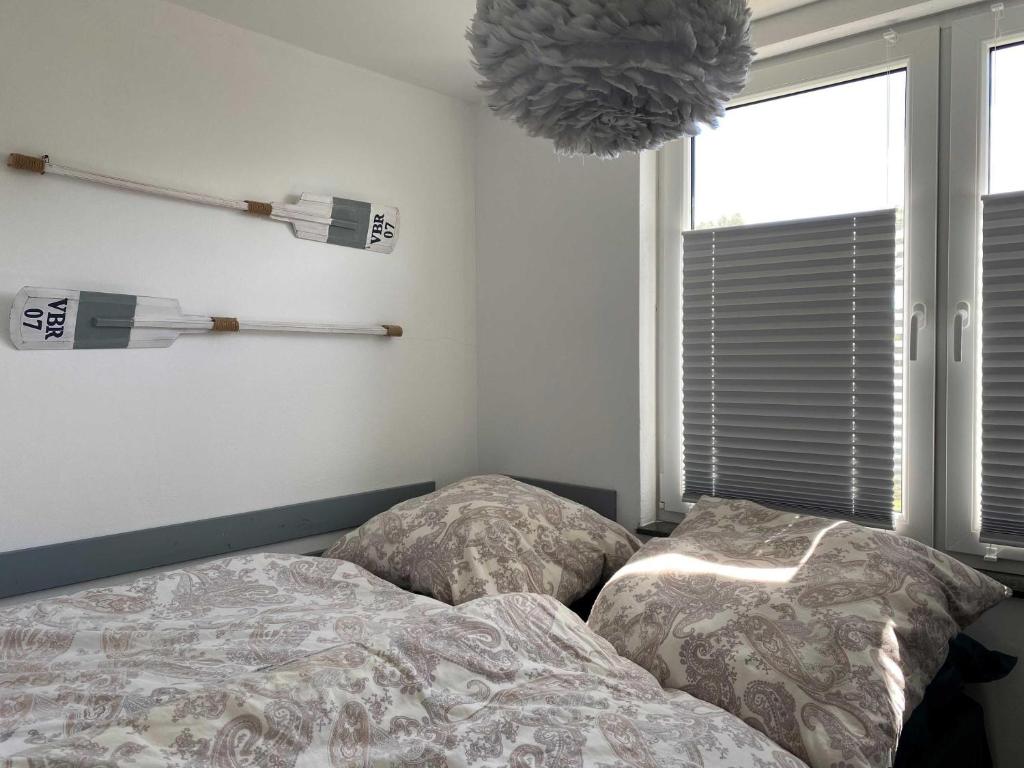 a bed with two pillows in a bedroom with a window at Kleiner Sommerweg Bungalow in Diedrichshagen