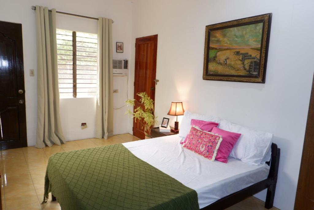 a bedroom with a bed with pink pillows on it at Villa Solaj Dumaguete in Aganan