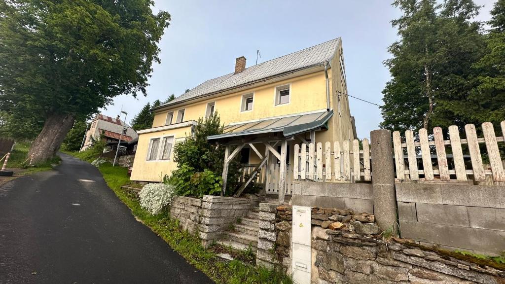 a yellow house with a fence next to a road at Chalupa Lázeňka in Pernink