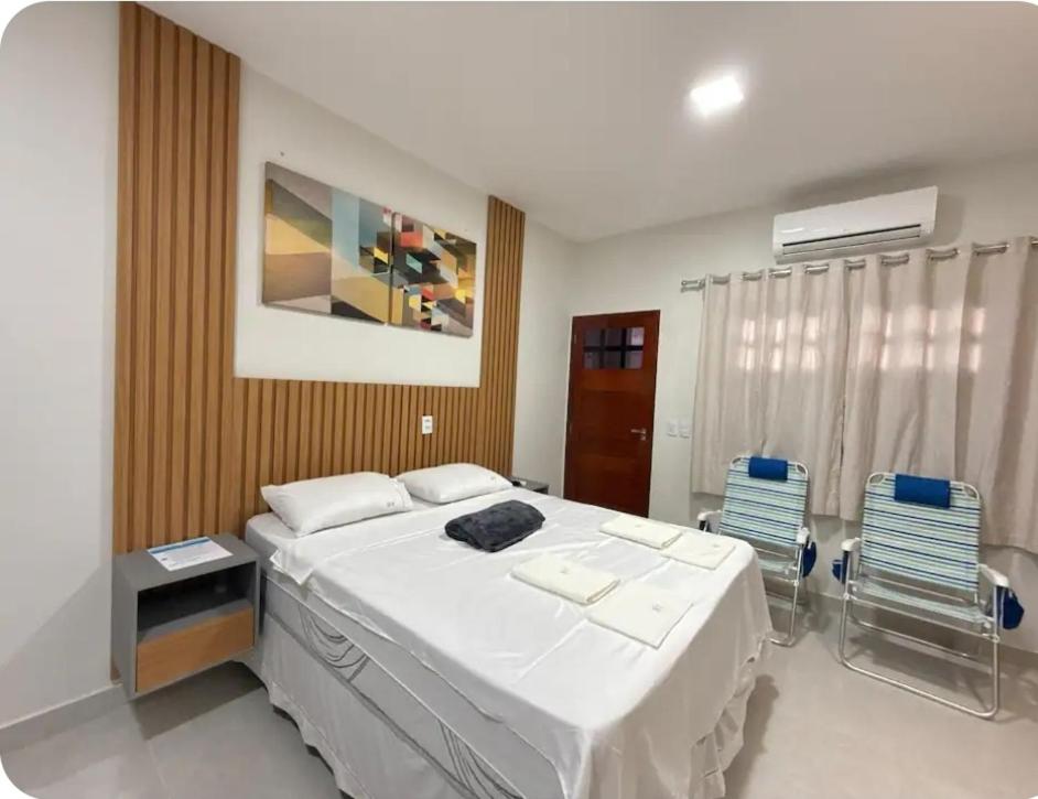 a bedroom with a large white bed and two chairs at Flat 11 Condomínio Ibiapaba Camocim in Camocim