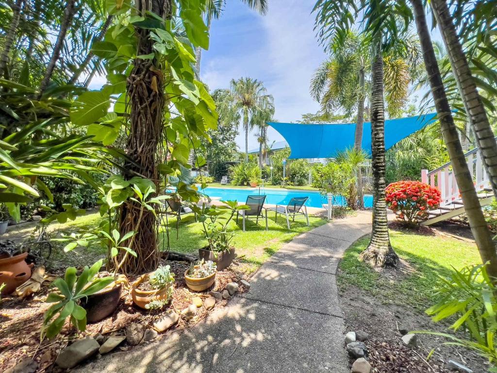 a path through a garden with palm trees and a swimming pool at Escape To Mango House in Airlie Beach