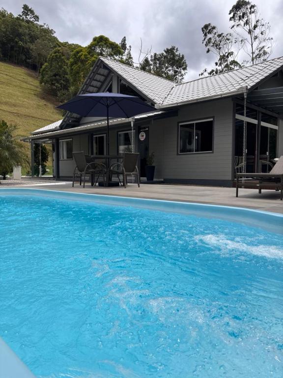 a house with a blue swimming pool in front of it at Sítio Monte Frederico in Nova Trento