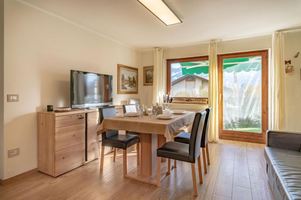 a dining room with a table with chairs and a tv at Trilo Ciasa Brìma in Carano