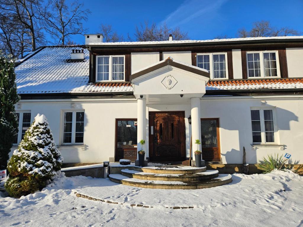 a white house with snow in front of it at Folwark Historic Hotel in Warsaw