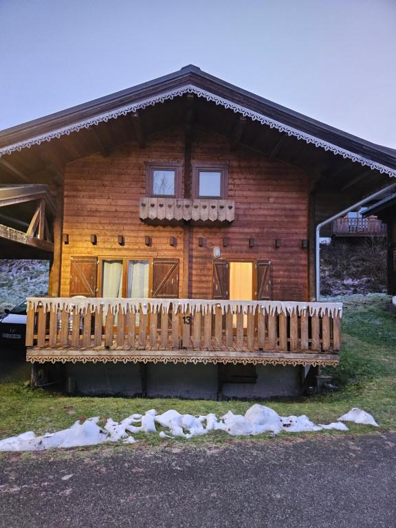 a wooden house with a porch and a deck at Chalet du Bief , Morillon 4-6 pers in Morillon