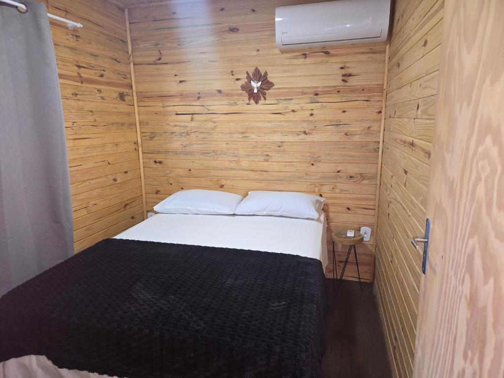 a small bedroom with a bed in a wooden wall at Casa Container Rosa in Bagé