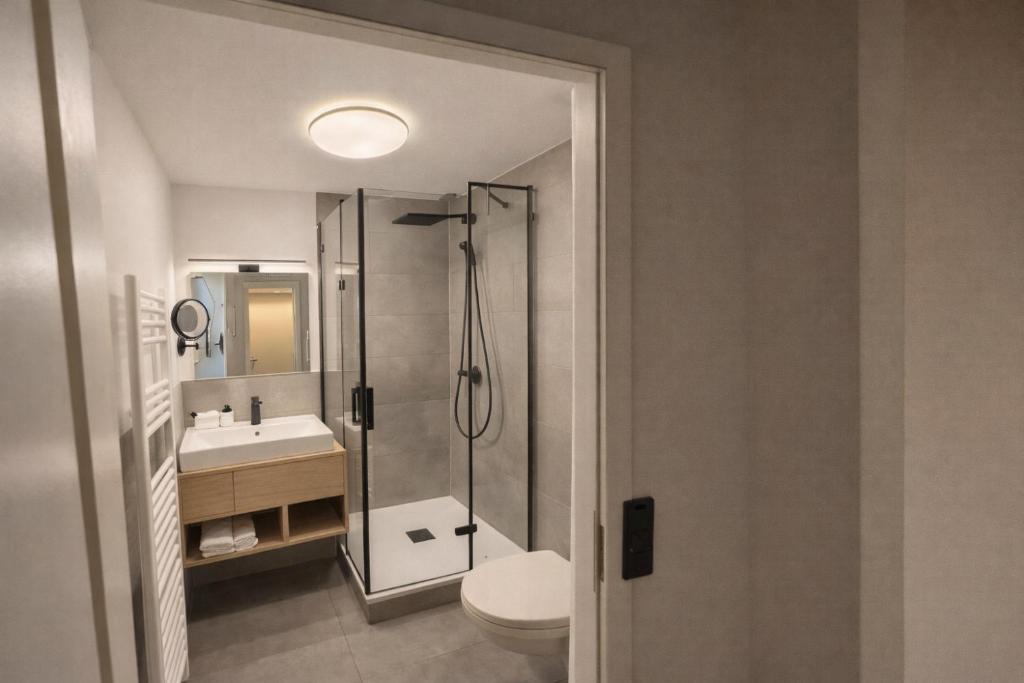 a bathroom with a shower and a toilet and a sink at BEELiving Augsburg in Augsburg