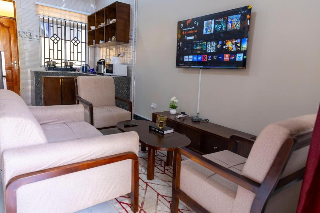 a living room with two white couches and a tv at Sastar Homes in Iringa