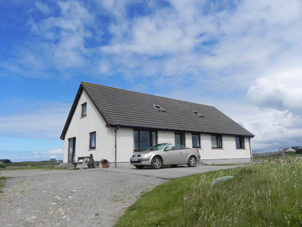 a car parked in front of a white house at Hebridean Stay in Creagorry