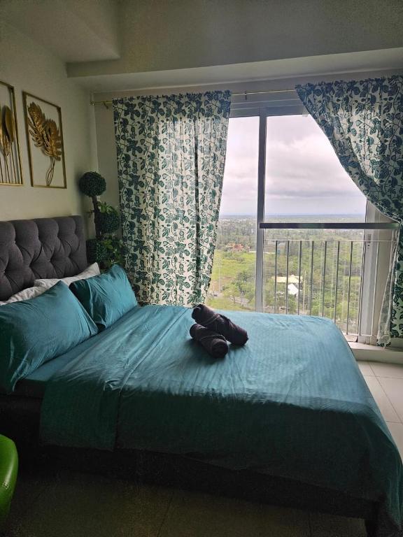 a bedroom with a large bed with a large window at Escapade in Tagaytay by JV in Kaybagal