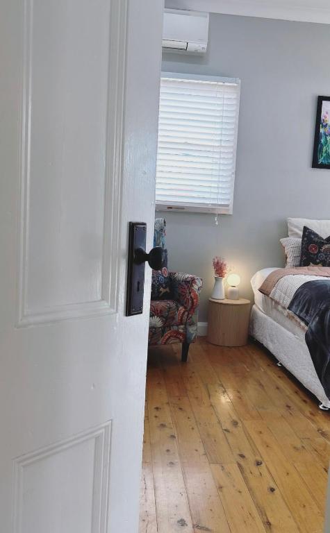 a bedroom with a bed and a door with a chair at The BnB filled to the brim with character & charm! in Dubbo