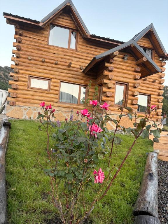 a log cabin with pink flowers in front of it at Cabañas Betsaida in Lago Meliquina