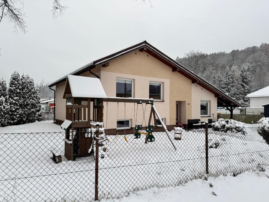 a house with a playground in the snow at Prázdninový dům Mladé Buky in Mladé Buky