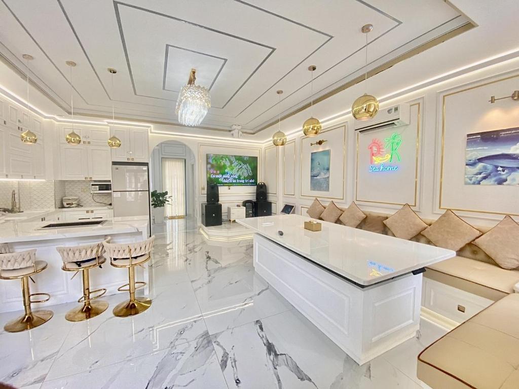 a white kitchen with a large island and bar stools at PKseahome 3 bedroom 4 toilet Novaworld in Phan Thiet
