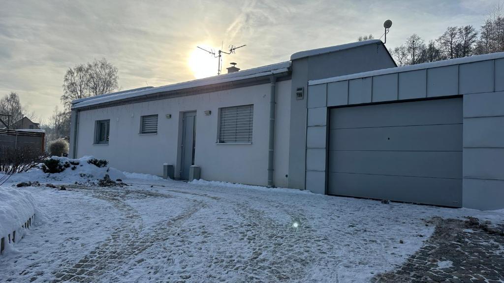 a white building with a garage in the snow at Apartmán 135 in Trutnov
