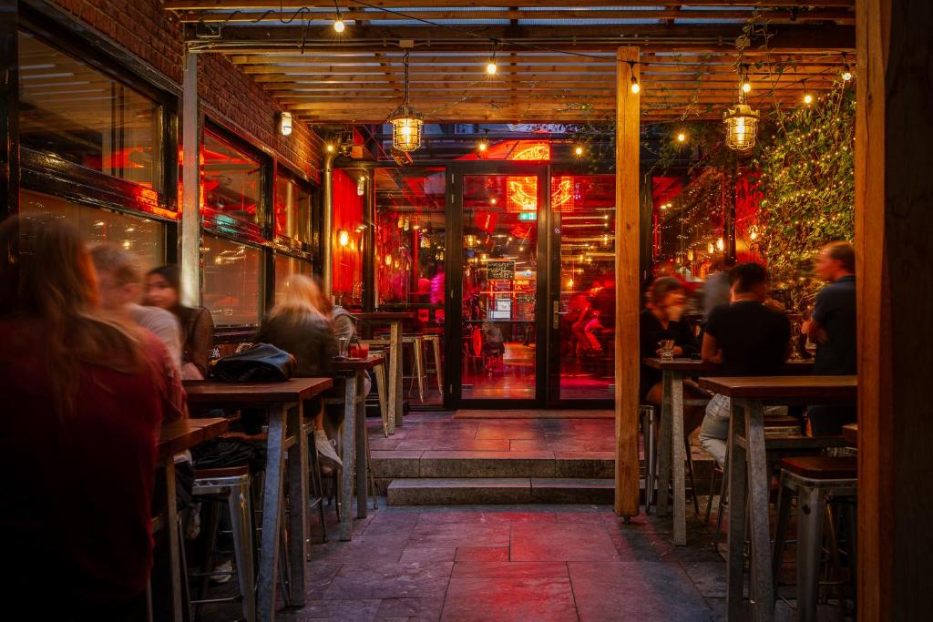 a group of people sitting at tables in a restaurant at St Christopher's Amsterdam - The Winston in Amsterdam