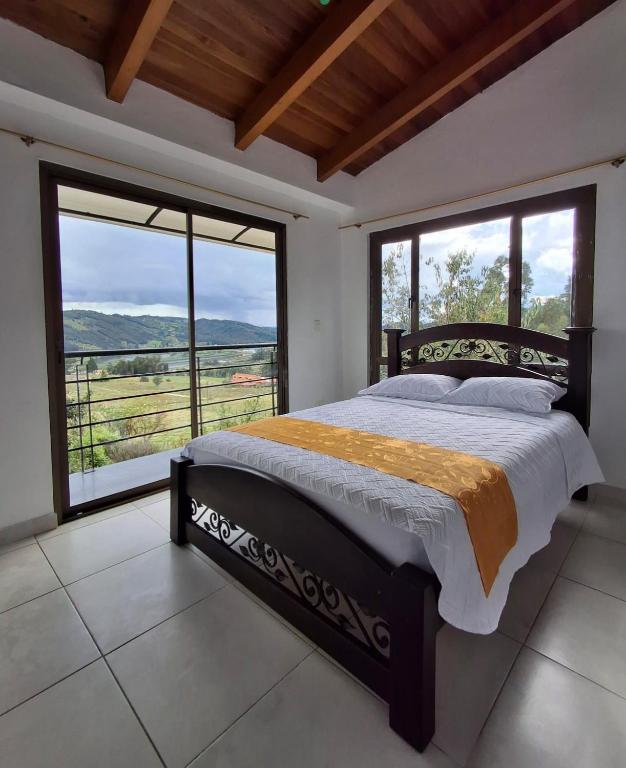 a bedroom with a large bed and large windows at Cabaña Campestre Bellavista in Paipa