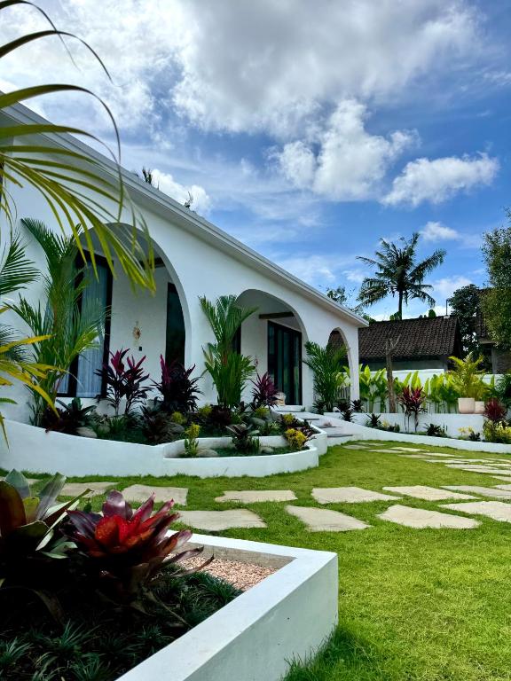 a white house with a garden in front of it at Casa De Made - Villas in Jembrana