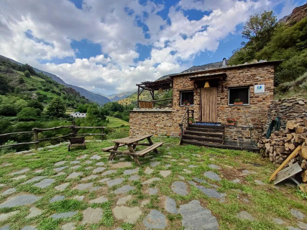 a stone building with a picnic table in front of it at CASA RURAL CORTIJO MOLINO ALTERO in Trevélez