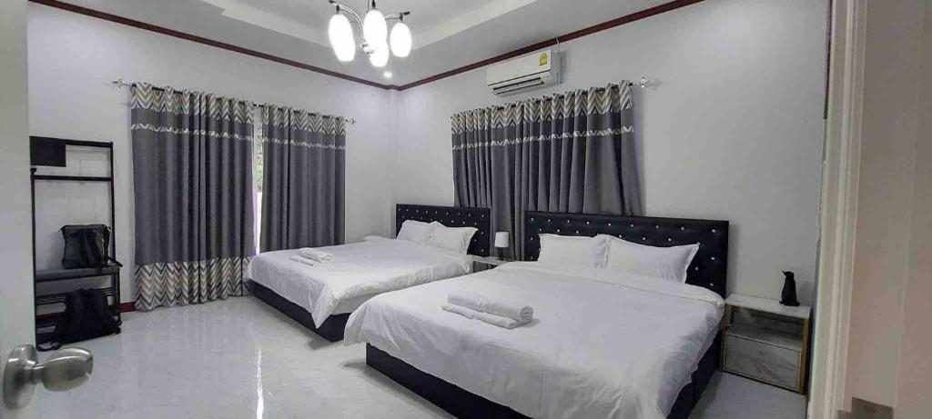 a bedroom with two beds and a television in it at The Natphop pool villa Meeting Pool Villa in Cha Am