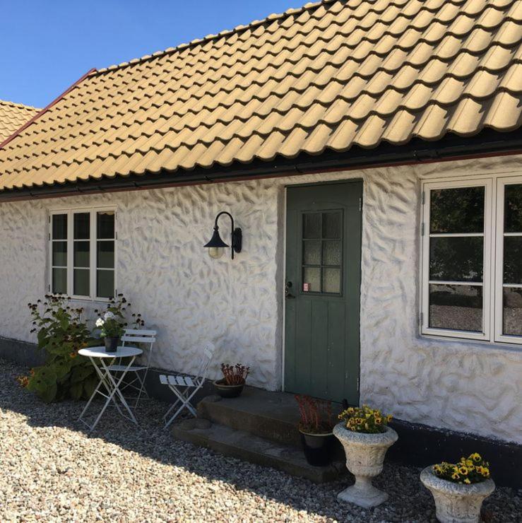 a white house with a green door and a table at Stugan på Skårby in Ystad