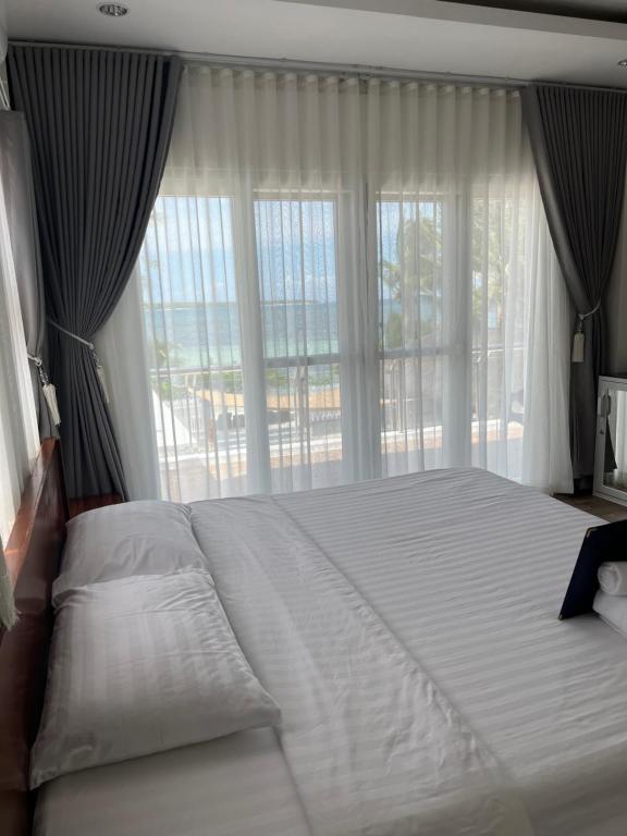a large bed in a bedroom with a large window at Maykenn Beach-Cafe Bar and Restaurant in Bantayan Island