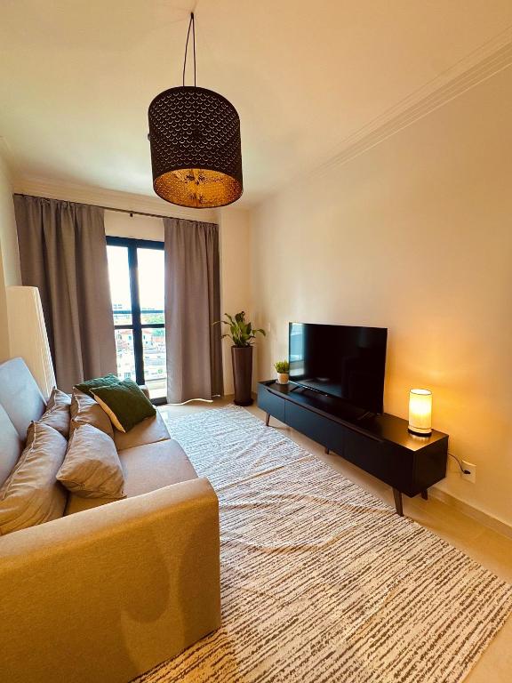 a living room with a couch and a flat screen tv at Apartamento completo e elegante no centro de Pouso Alegre in Pouso Alegre