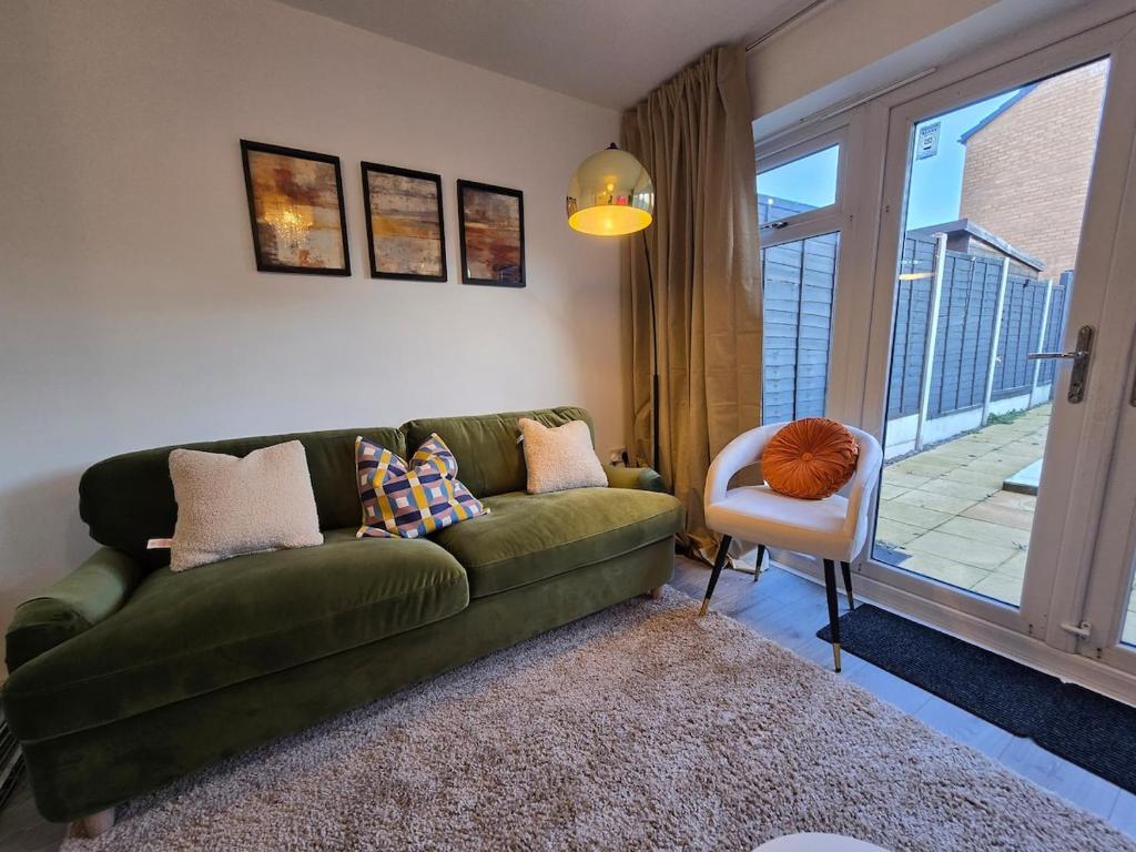 a living room with a green couch and a chair at Cozy Gem Luxury House in Marston Green