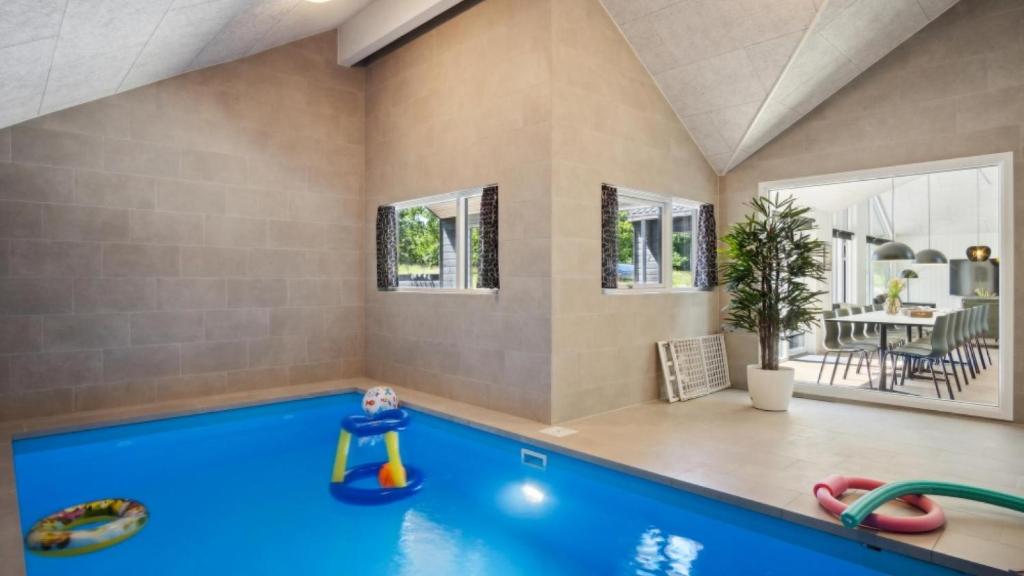 a swimming pool in a living room with a house at Villavilla 640 - Saksild, Østjylland in Odder