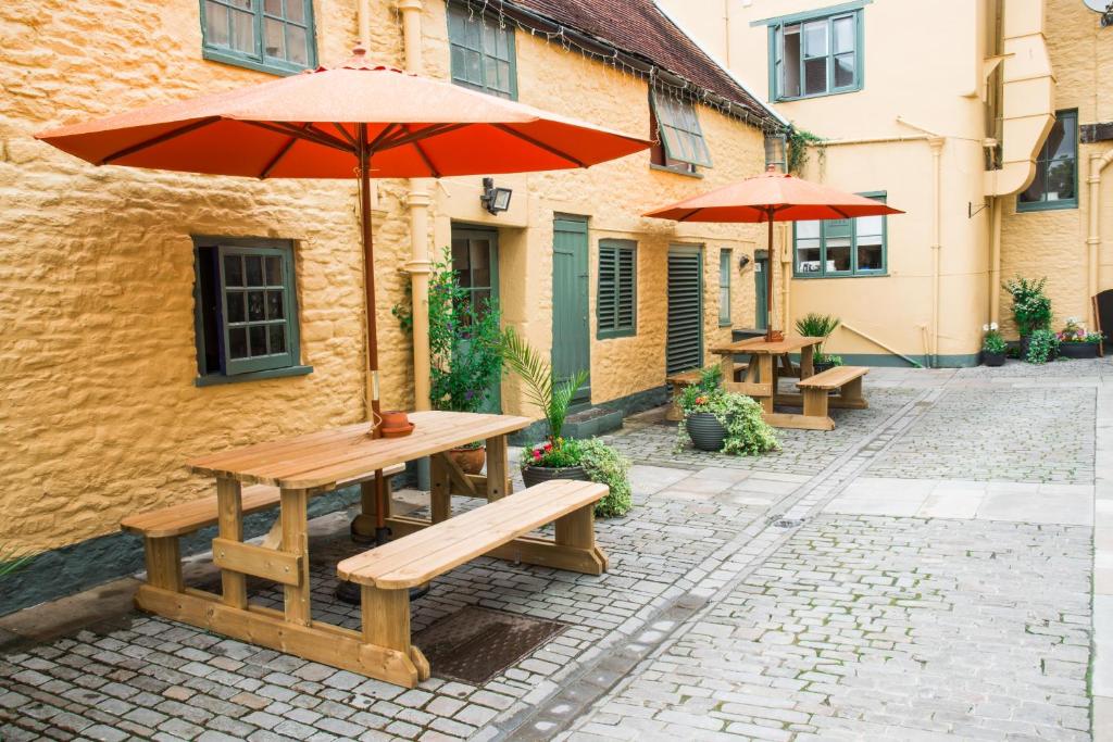 a wooden picnic table with an umbrella on a street at The Dolphin Hotel in Wincanton