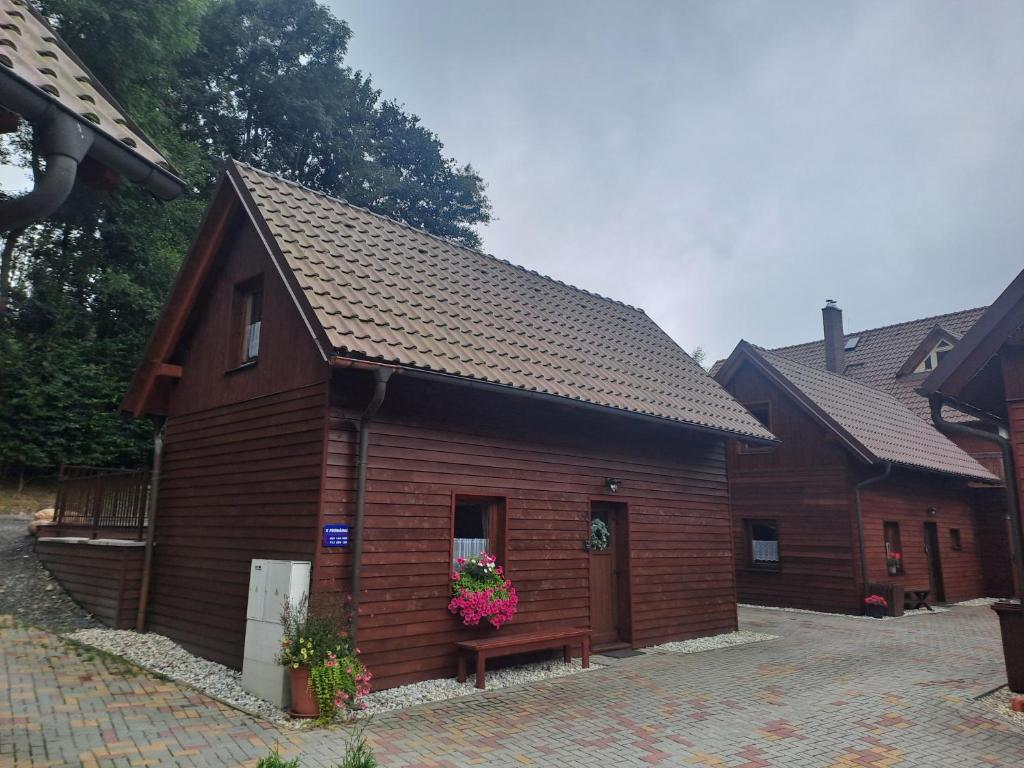 a small wooden building with flowers in front of it at Chaty Hrubý in Dolní Moravice