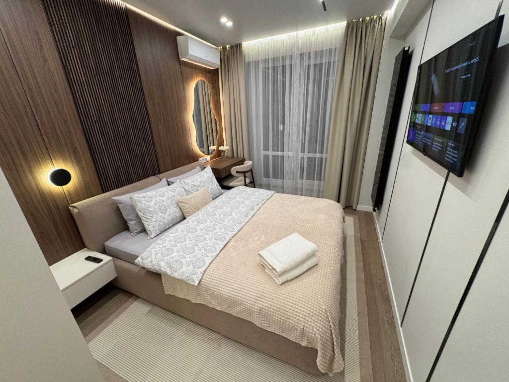 a small bedroom with a bed and a television at RentNow Apartments Luxury Apartment with Balcony and Parking in Chişinău